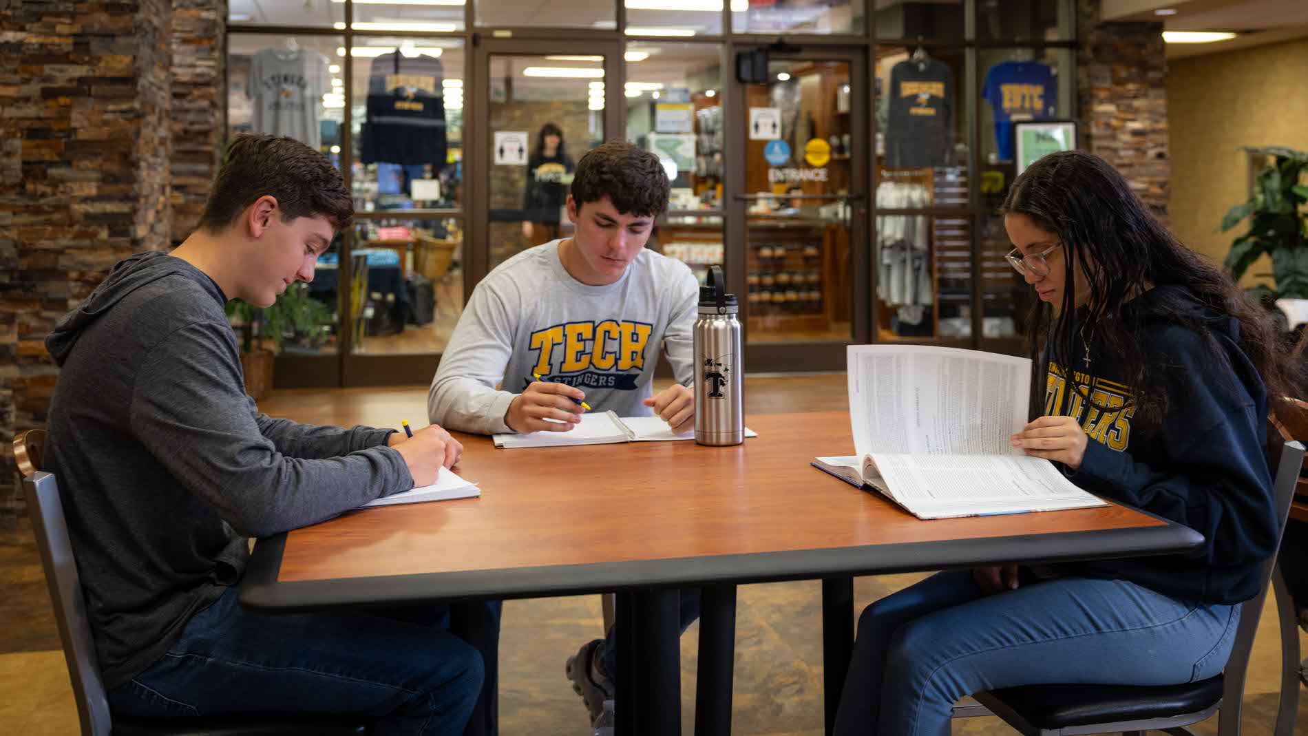 A group of students study in front of the college book store.