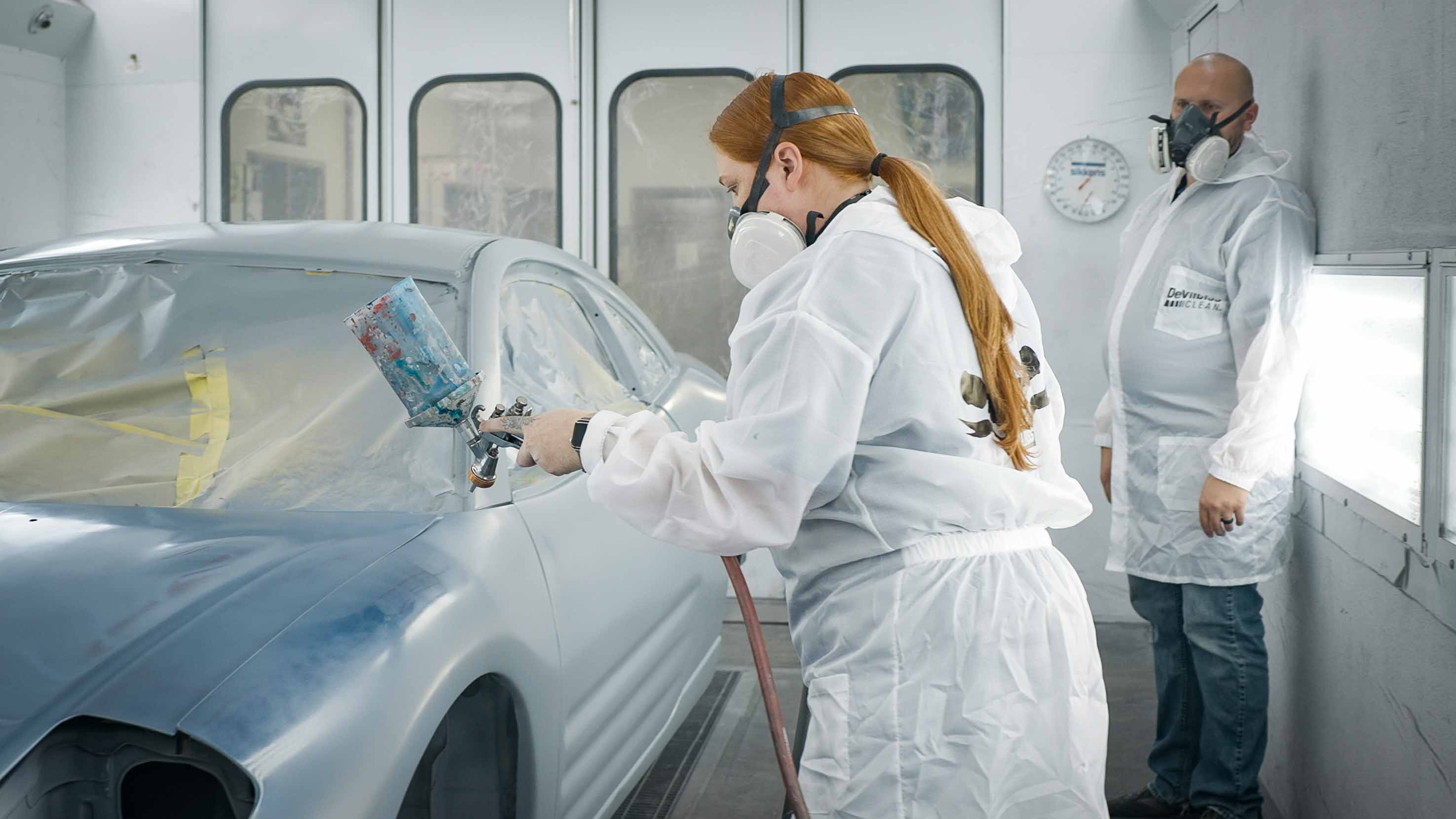 A husband and wife are painting a car together in the Auto Body class.