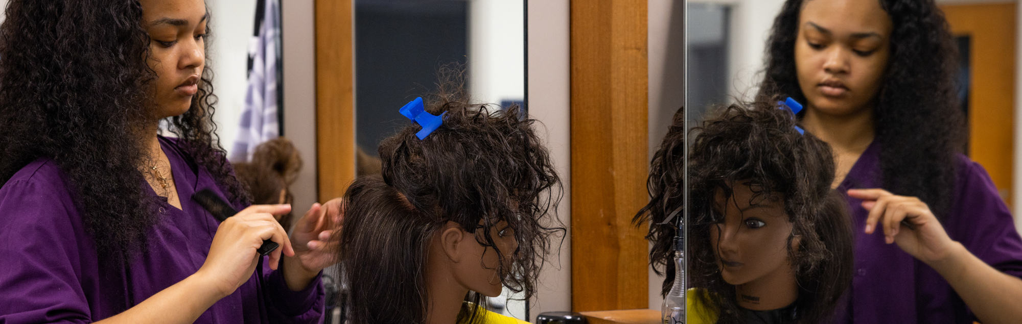A cosmetology student practicing to become a hair stylist at the Cosmetology school