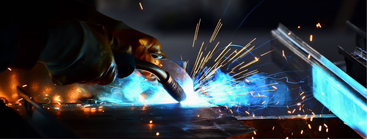 A close up image of a welder in action with fire and sparks