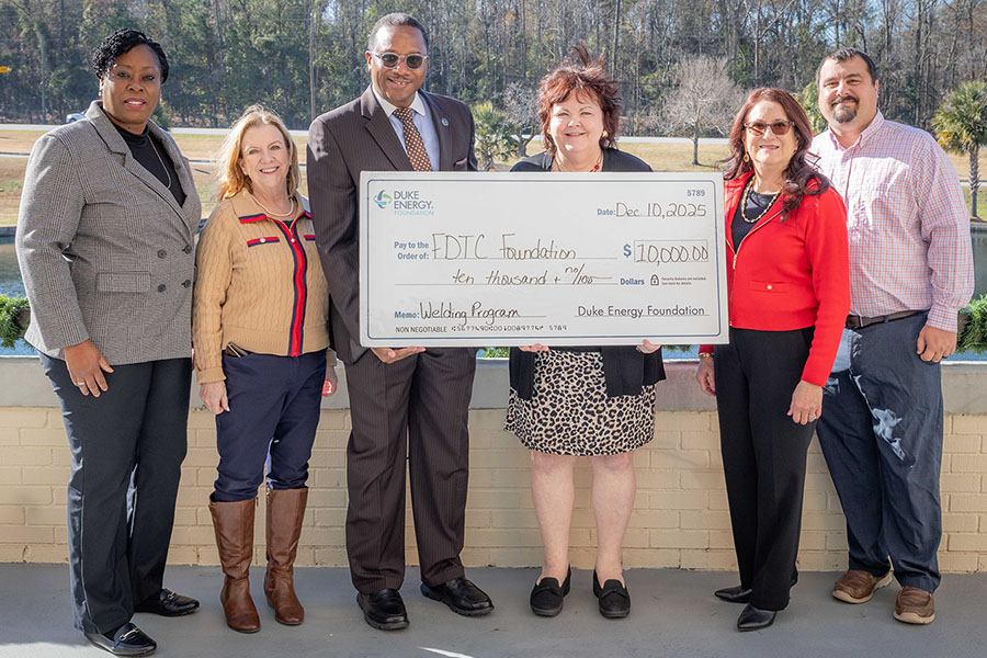 Officials with FDTC and Duke Energy pose with a giant check