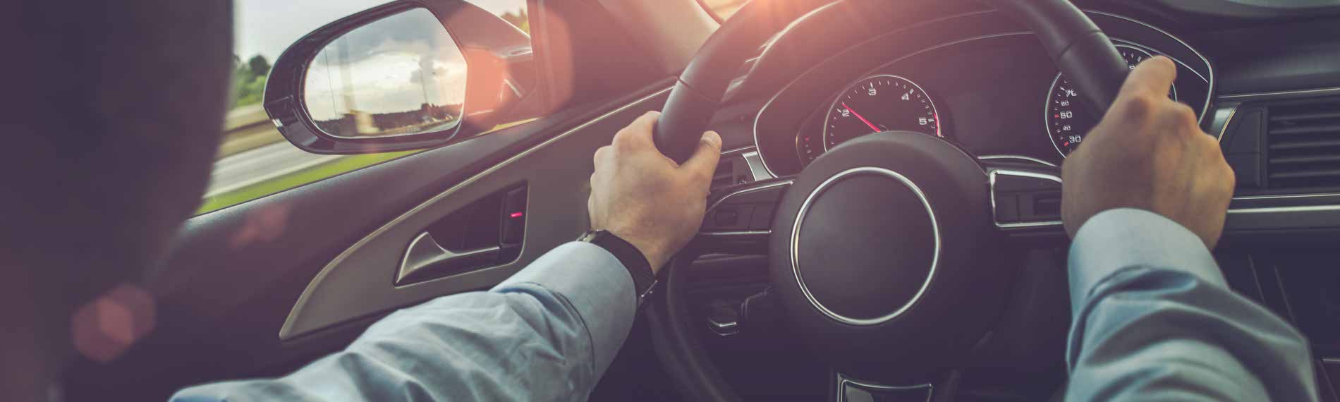 An interior photo of a car with a man seated in the drivers seat driving.